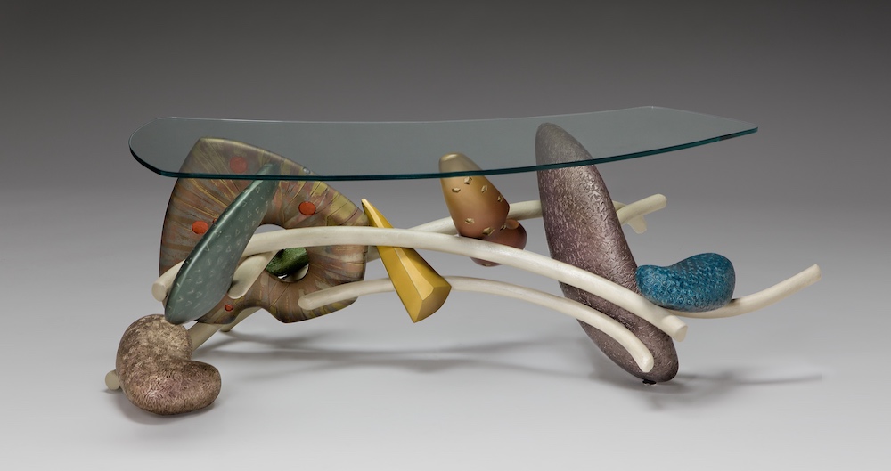 glass table with curving wooden lines and various carved objects