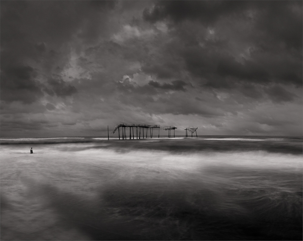 person in ocean with deteriorating pier