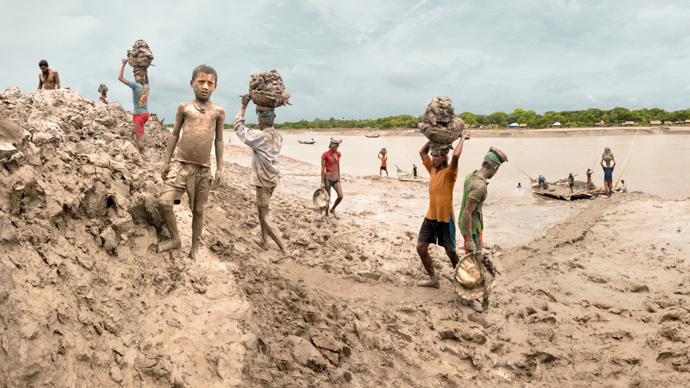 people carry baskets of mud from river with child playing