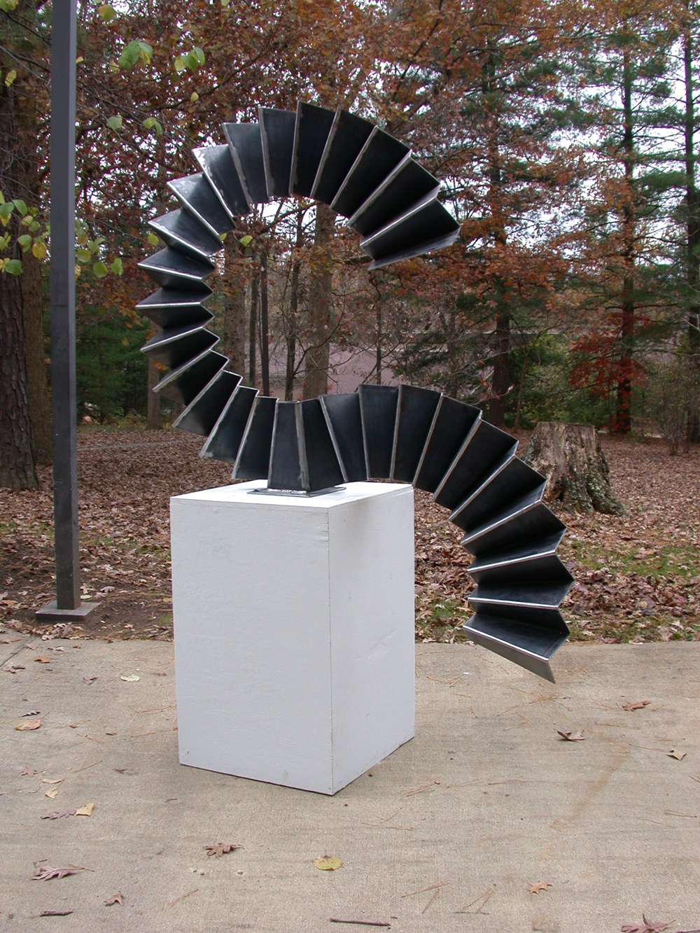accordion bent steel in s-curve rests on pedestal