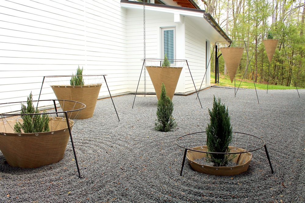 burlap cones and steel supports hold evergreens trees in spiraling form in courtyard