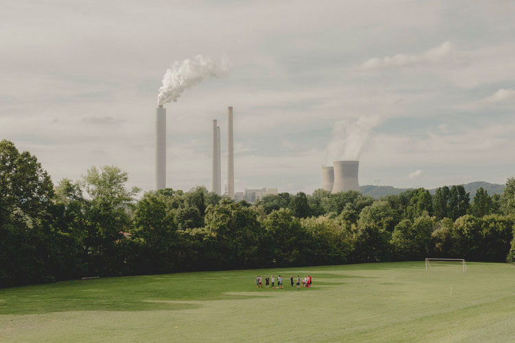 Group of soccer players in field with smokes stacks in background