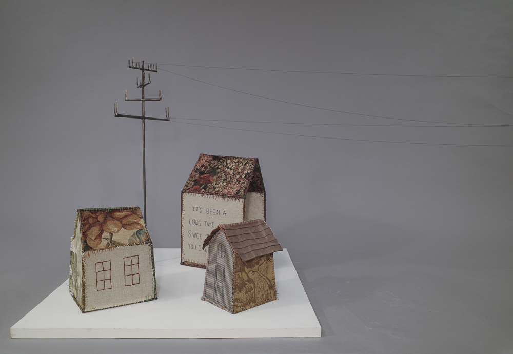 Steel sculptures of power lines homes covered in fabric