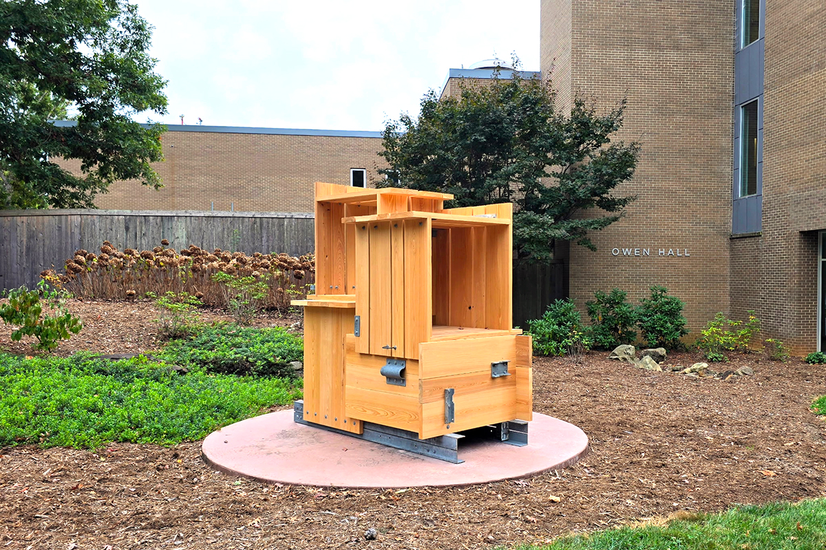 wood and metal sculpture in front of large building