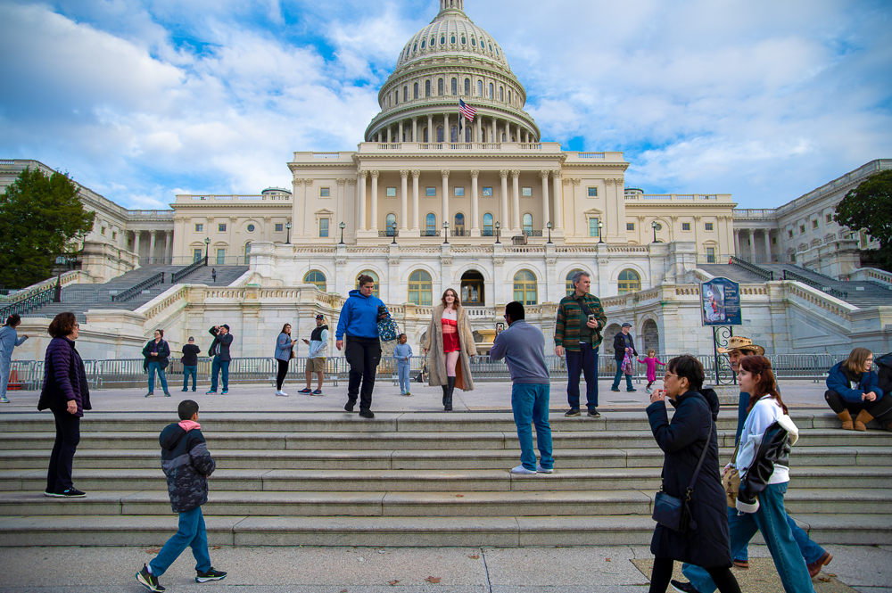 Image of woman in red dress walking down the steps of the US Capital with onlookers watching