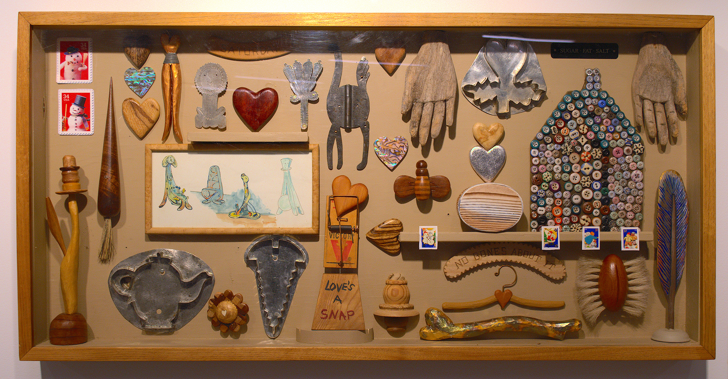 Wooden frame with carvings, cookie cutters, stamps, buttons and hinges.