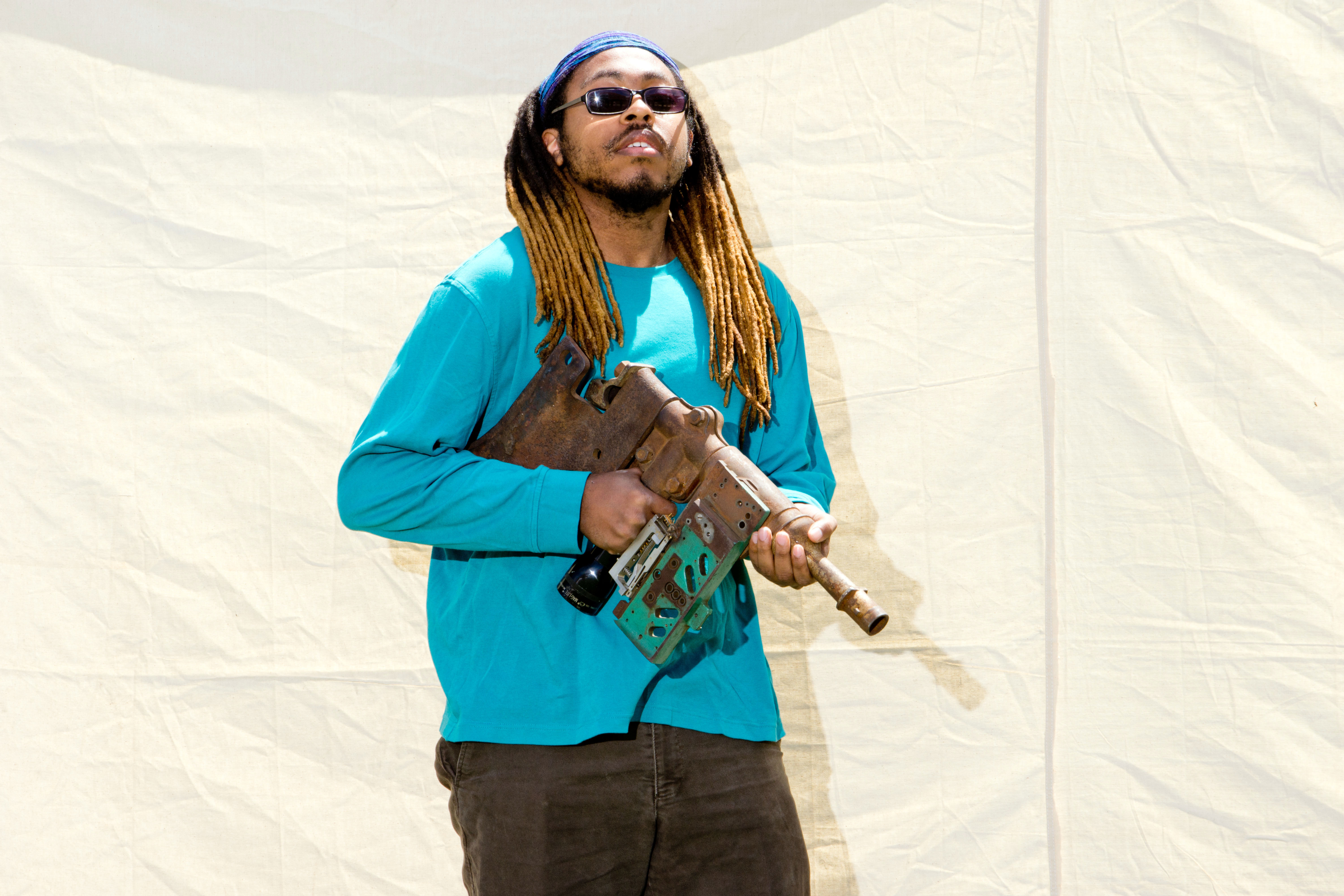 Student with blue shirt holds mock assault rifle and posses for photo