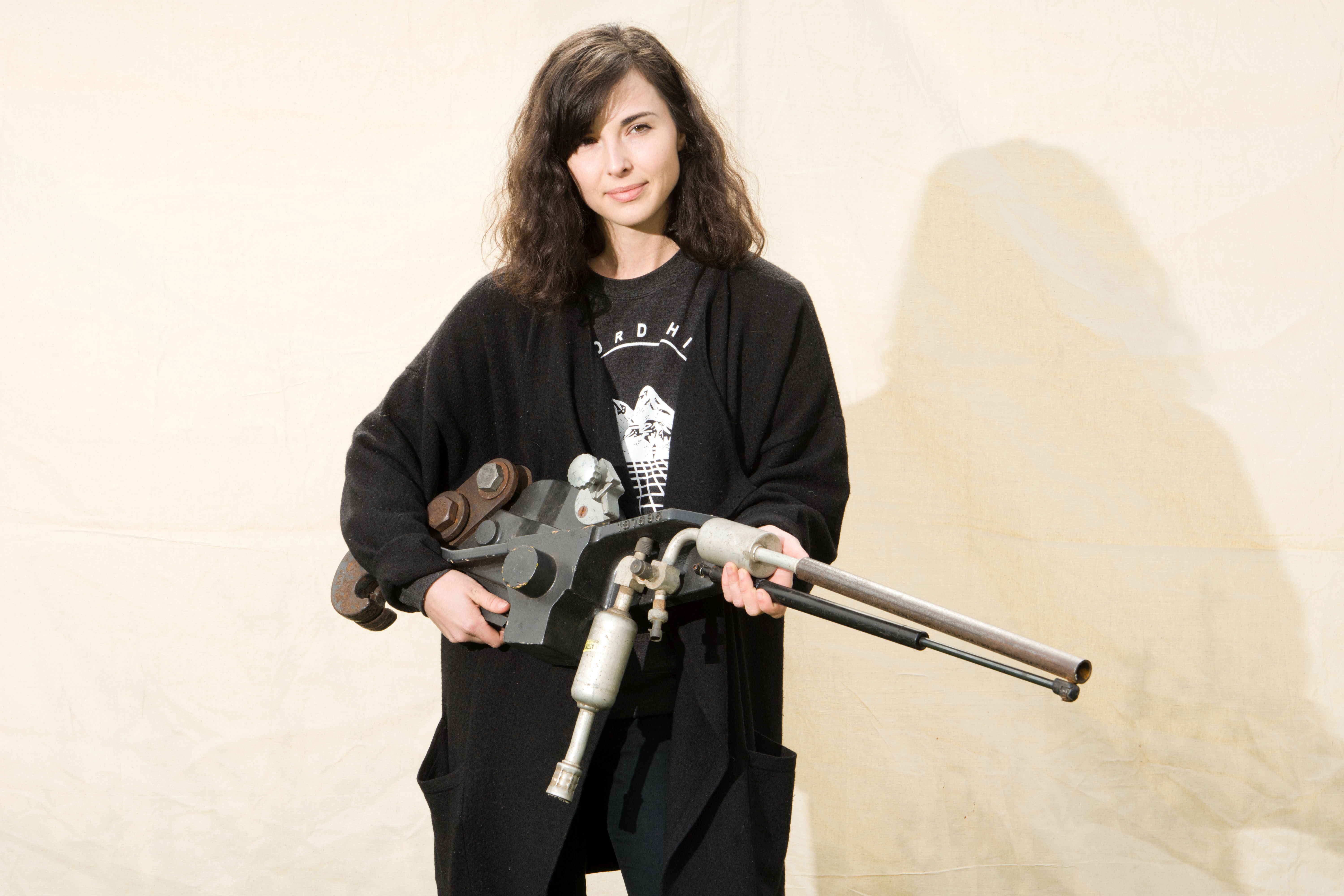 Student in black jacket holds mock assault rifle and posses for photo